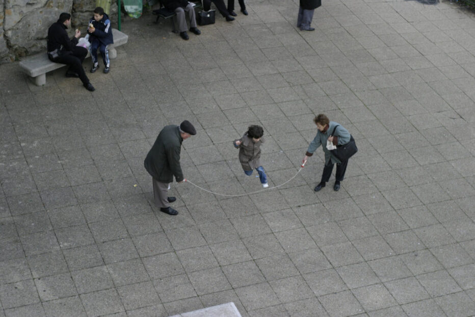 Two elderly people playing jump rope with a child